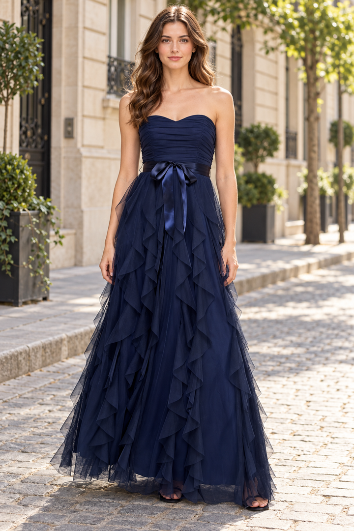 Stunning navy blue prom dress featuring an elegant strapless sweetheart neckline adorned with delicate tulle ruffles and a graceful bow accent. Perfect for creating an unforgettable entrance at any formal event.&nbsp;